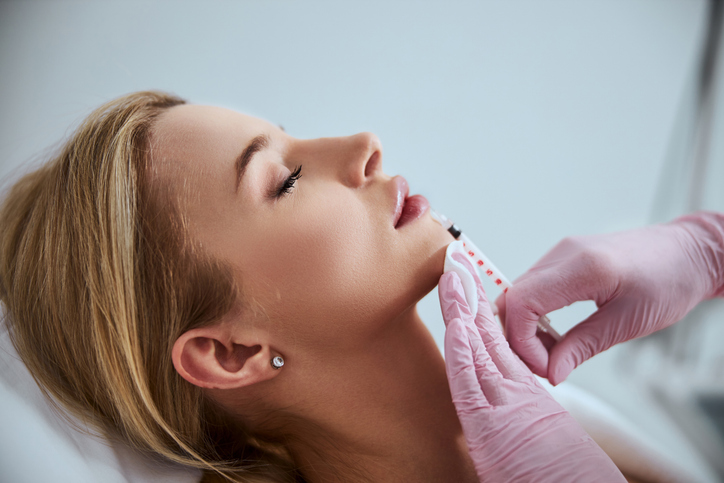 Professional dentist injecting a dermal filler into the patient lips