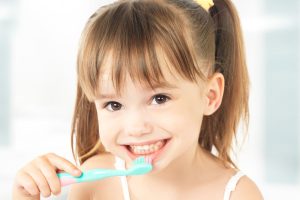 Smiling young girl smiling while brushing teeth